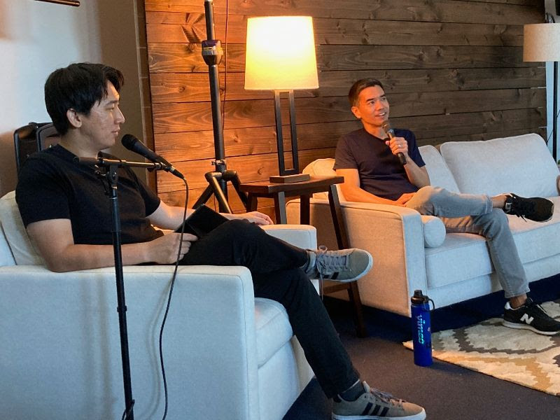 Chris sits down on the couch with John